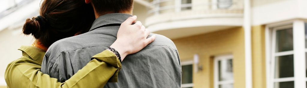 Ein Paar hält sich in den Armen und begutachtet eine Immobilie.